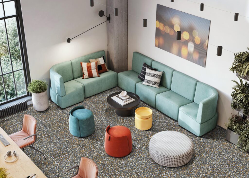 Ambiente lounge moderno con ampie sedute modulari verde salvia e pavimento effetto terrazzo Serie D_Lash colore Saffron Terracotta. Superficie in gres porcellanato dal design materico e contemporaneo, ideale per spazi hospitality e contract dal carattere creativo ed elegante.