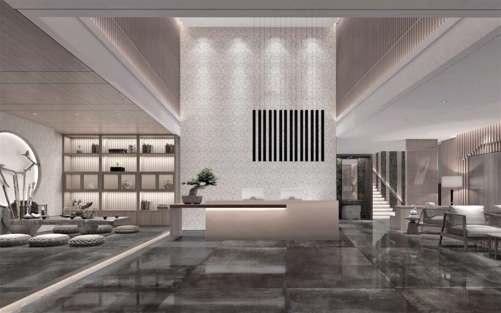 La collezione Hemisphere Iron 80x80 in finitura lappata riveste con eleganza il pavimento di una lussuosa hall d'hotel. Le grandi piastrelle scure dall'effetto metallico riflettono la luce, creando un'atmosfera sofisticata in un ambiente di design d'ispirazione zen. Al centro, un bancone reception minimalista con un bonsai è affiancato a sinistra da una suggestiva area lounge con sedute basse e pareti in legno retroilluminate.