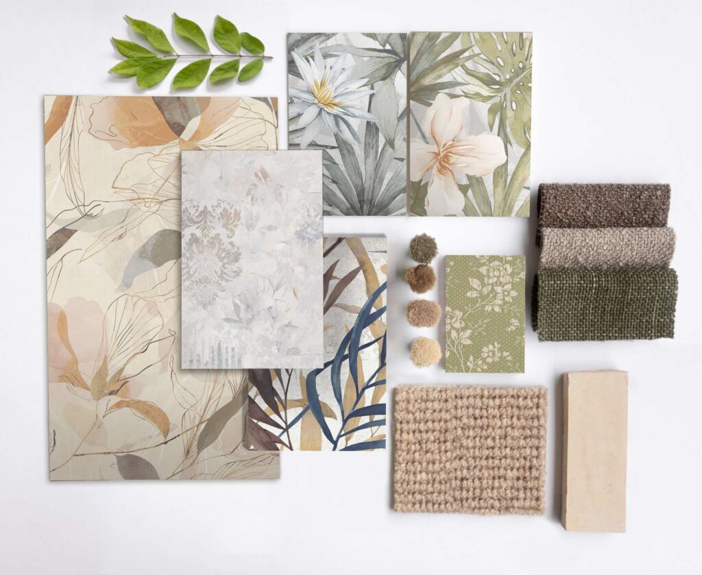 Collezione I-DECORS: una raffinata moodboard in stile flat lay che presenta piastrelle ceramiche in vari formati decorativi. I campioni esposti mostrano eleganti motivi floreali, botanici e damascati in una palette naturale di beige, verde salvia, crema, terracotta e dettagli blu. Completano la composizione elementi materici coordinati come campioni di tessuto bouclé, piccoli filati, un elemento in pietra e un ramo verde su fondo bianco, ideali per ispirare progetti d'interni dal design armonioso e d'eccellenza.